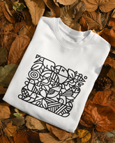White sweatshirt with black geometric design on a bed of autumn leaves